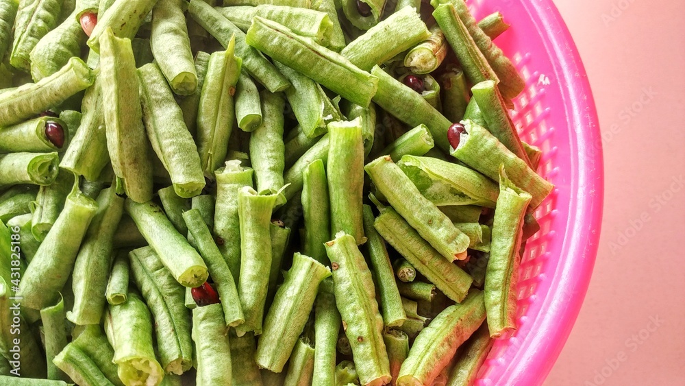 Long bean vegetables Vigna Unguiculata which have been cut into pieces ready to be cooked as a meal menu. In a basket and pink background