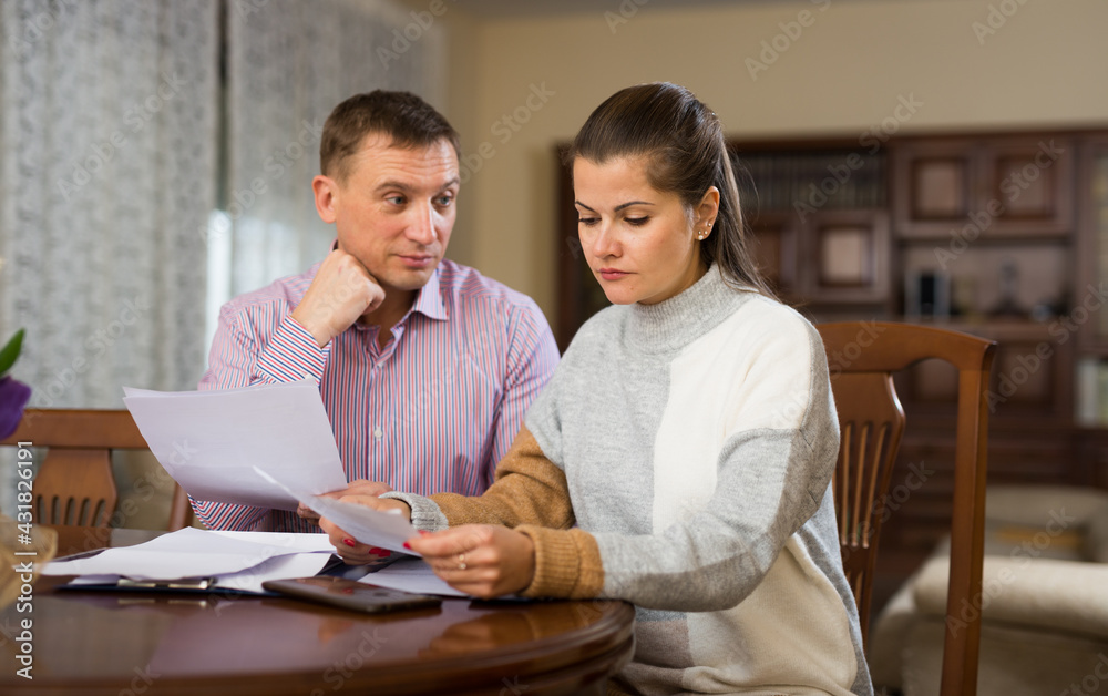 Adult family couple reading mail together and checking accountancy in home interior