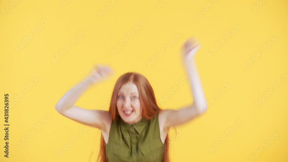 Woman with freckles and long ginger hair is appearing in the frame and dancing in a funny way. Yellow background Woman with freckles and long ginger hair is appearing in the frame and dancing in a funny way. Yellow background