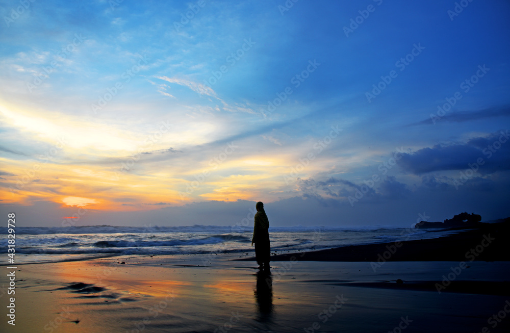 Silhouette of  a person enjoying sunset on the beach at Yeg Gangga beach in Bali Indonesia