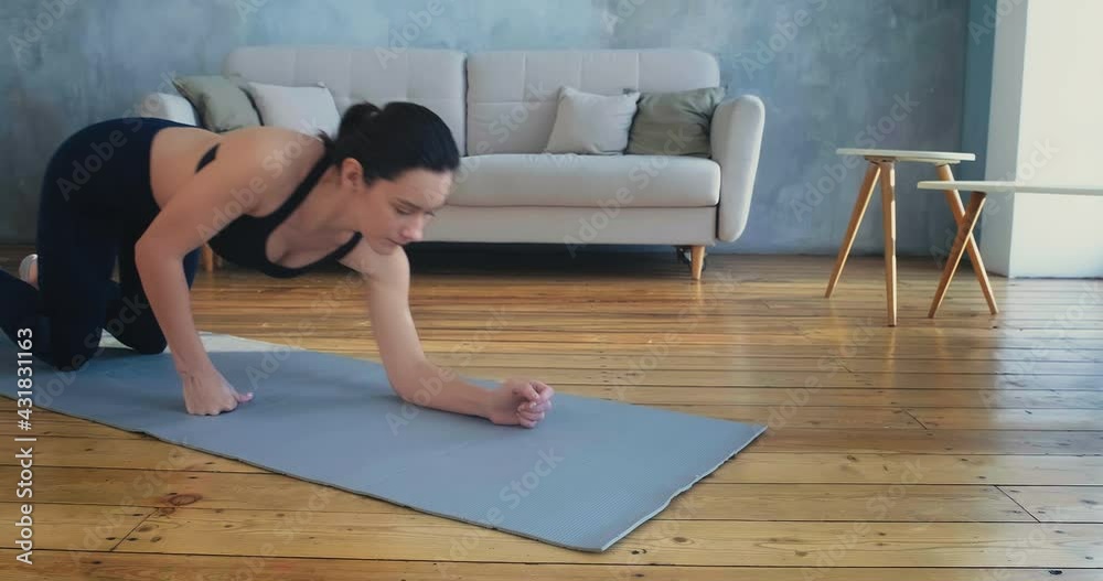 Sportive woman in tracksuit does plank exercise in room Sportive woman in tracksuit does plank exercise in room