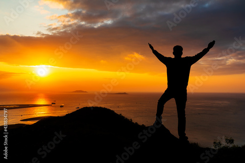 Young man standing in the mountains at sunrise and enjoying view of nature.