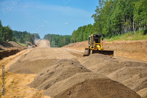 the tractor scraper levels the ground of the new road. Construction of a new road