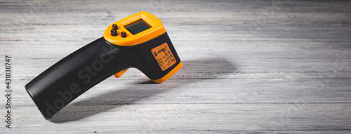 Yellow-black pyrometer on a wooden background. A device for non-contact temperature measurement. photo