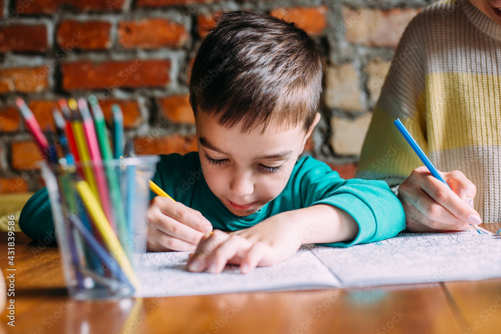 Portrait of a cute happy preschool boy at home or in a cafe draws. Portrait of a cute happy preschool boy at home or in a cafe draws.