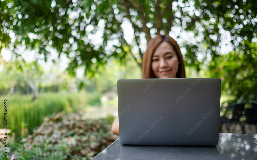 A young asian woman using and working on laptop computer in the park A young asian woman using and working on laptop computer in the park