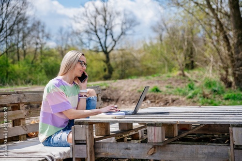 Woman with glasses working outdoors on a beautiful sunny day. Traveling with the computer.