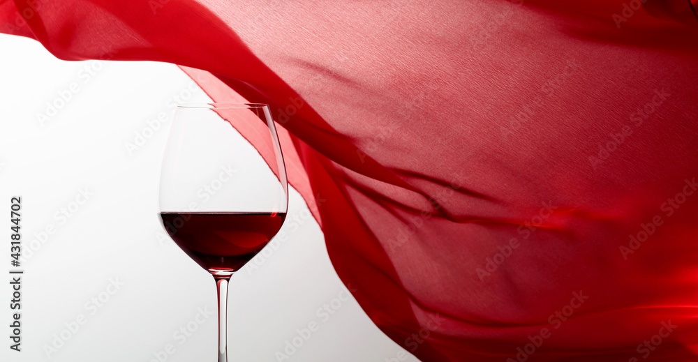 Glass of red wine on a background of waving red curtain. - obrazy, fototapety, plakaty 