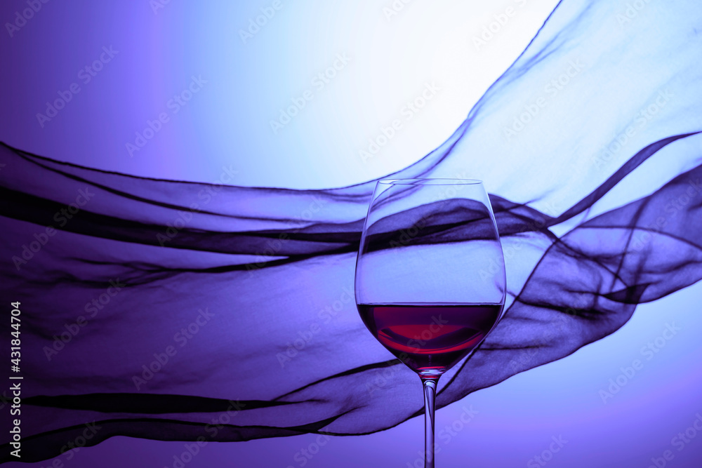 Glass of red wine on a background of waving curtain. - obrazy, fototapety, plakaty 