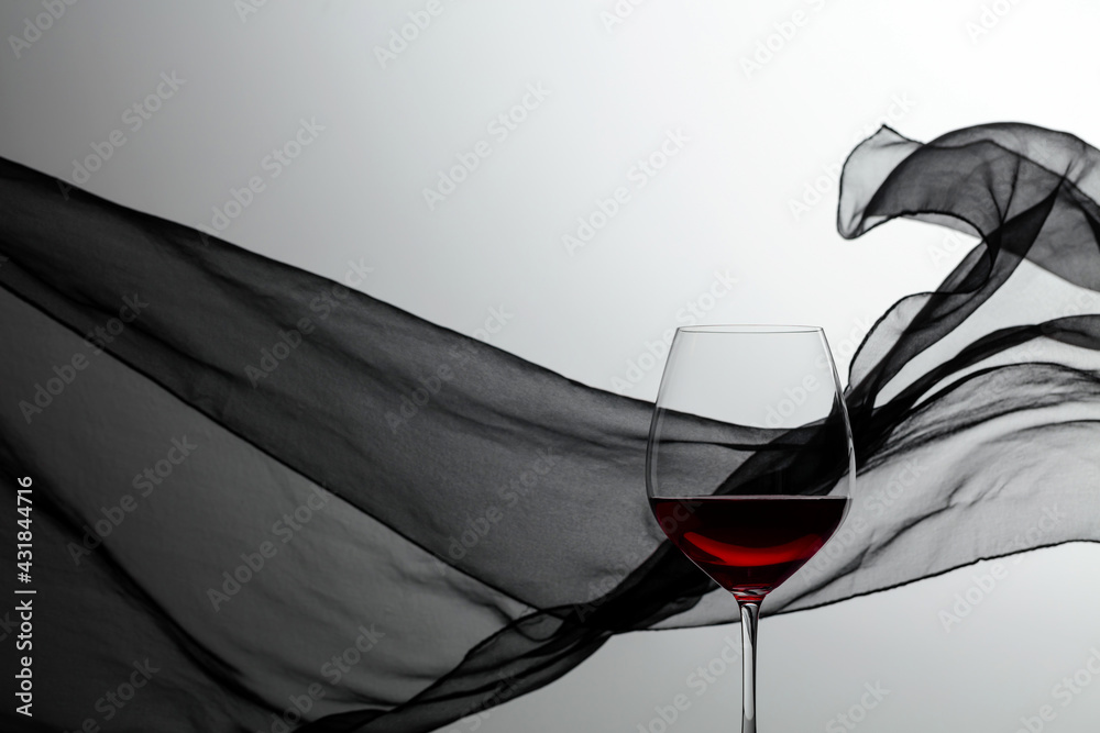 Glass of red wine on a background of waving black curtain. - obrazy, fototapety, plakaty 