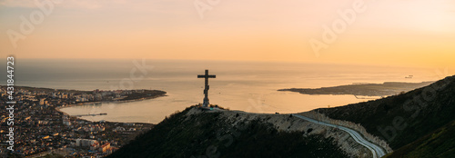 Gelendzhik, Russia, 03 May 2021: Orthodox cross on Markotkh ridge on background of Gelendzhik Bay during sunset.