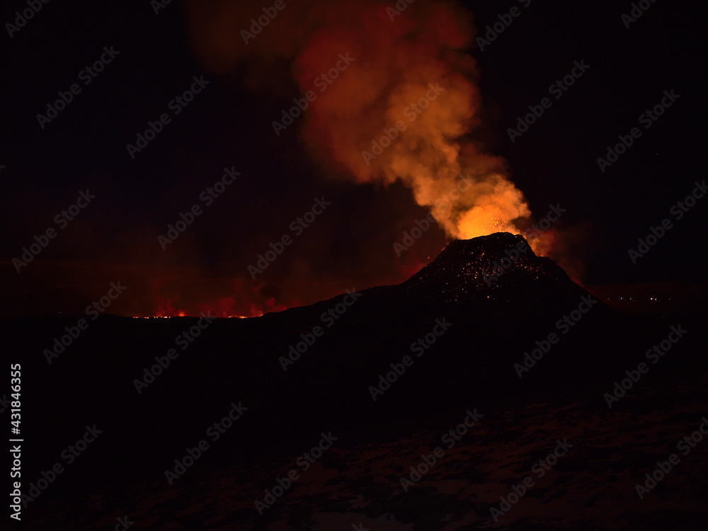 Stunning view of volcanic eruption in Geldingadalir valley near Fagradalsfjall mountain, Grindavík, Reykjanes peninsula, southwest Iceland in the night with red colored smoke and glowing lava.