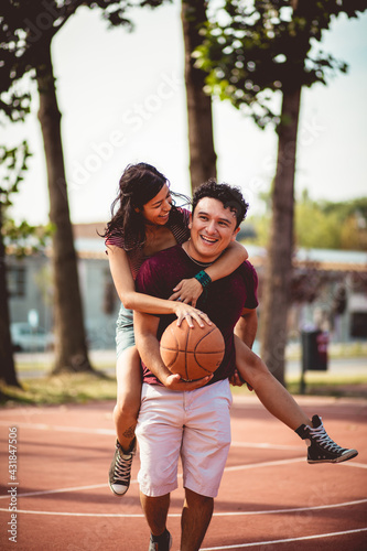 Young couple playing basketball on street court. © liderina