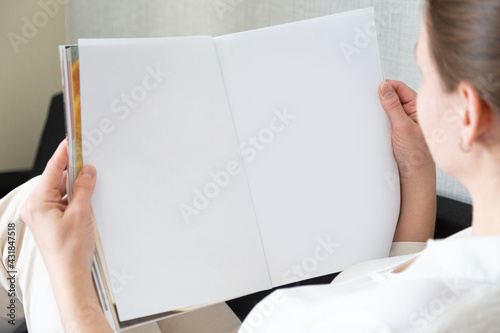 beautiful female hands holding white magazine with blank cover mock up at home