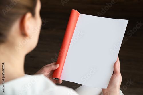 top view of a woman reading an open book or magazine. empty page. mock up