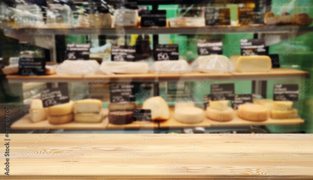 Mock up template, wooden table top, desk top counter in foreground for your product or text. Defocused blurred image of shelves with variety sorts of cheese. Farm craft view out of focus add template.