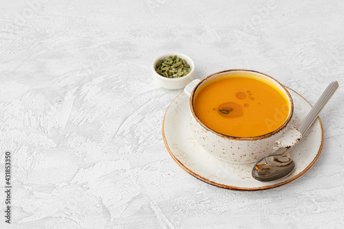 Blended pumpkin soup in bowl on gray background