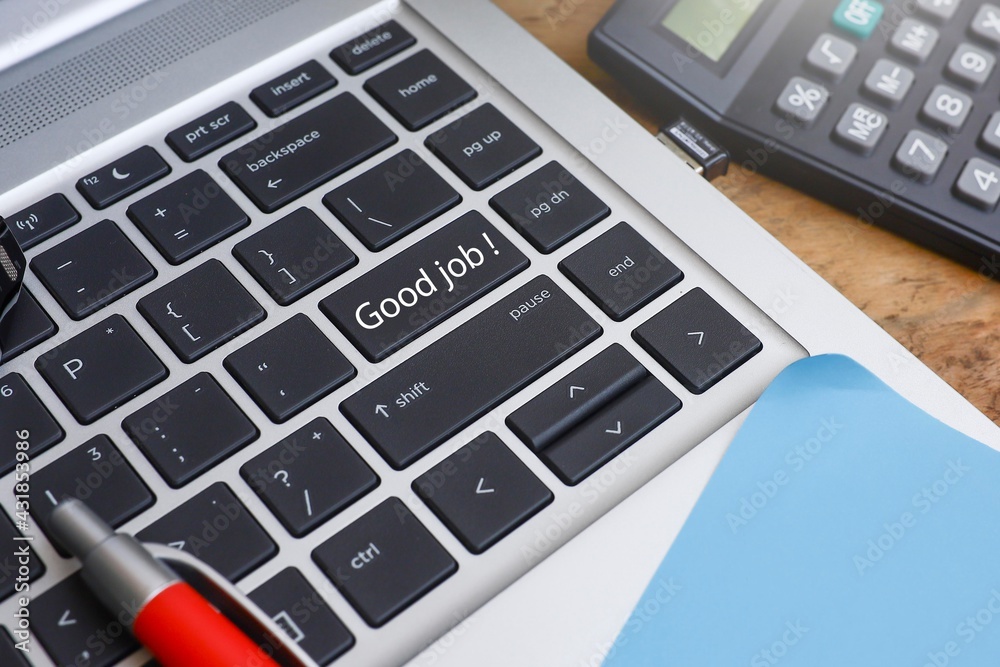 Text on Good Job written on the keyboard button with a pen, a piece of paper, and a calculator on the wooden table Text on Good Job written on the keyboard button with a pen, a piece of paper, and a calculator on the wooden table