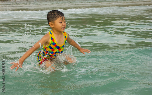 boy playing in the waves at sea in Thailand,cute baby have fun on vacation.