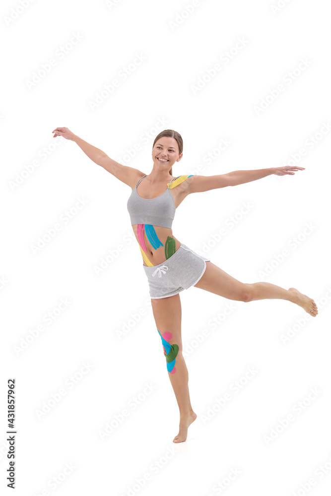 Kinesiology taping. Kinesiology tape on patient knee, belly, shoulder. Young female athlete doing exercises. Post traumatic rehabilitation, weight loss, cellulite removal, sport physical therapy.