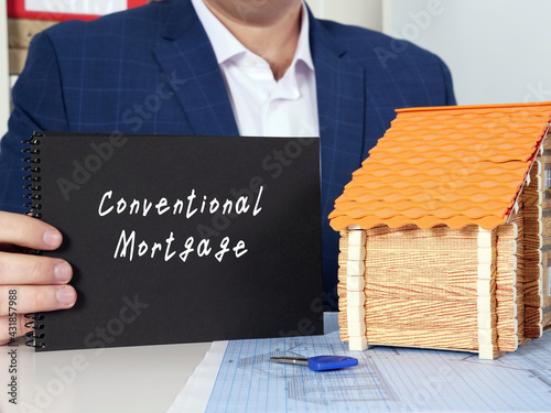Blank black notepad in a hand with phrase Conventional Mortgage . Horizontal shot.