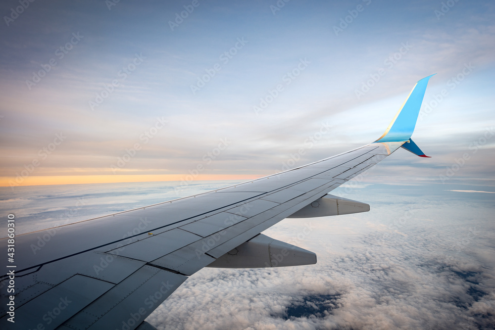 Obraz premium Commercial airplane while flying above the clouds at sunset. Looking through the plane window.