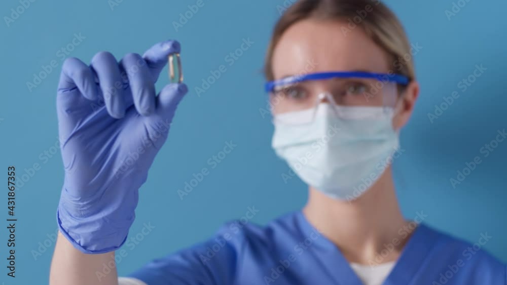 Medical practitioner holding up and inspecting a cupsule at work. Healthcare concept