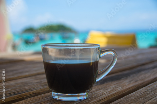 Black coffee on the wooden table, beachside, travel concept , nature light. Thailand