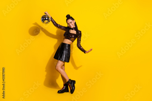 Full size photo of young attractive black woman happy positive smile hold disco ball isolated over yellow color background