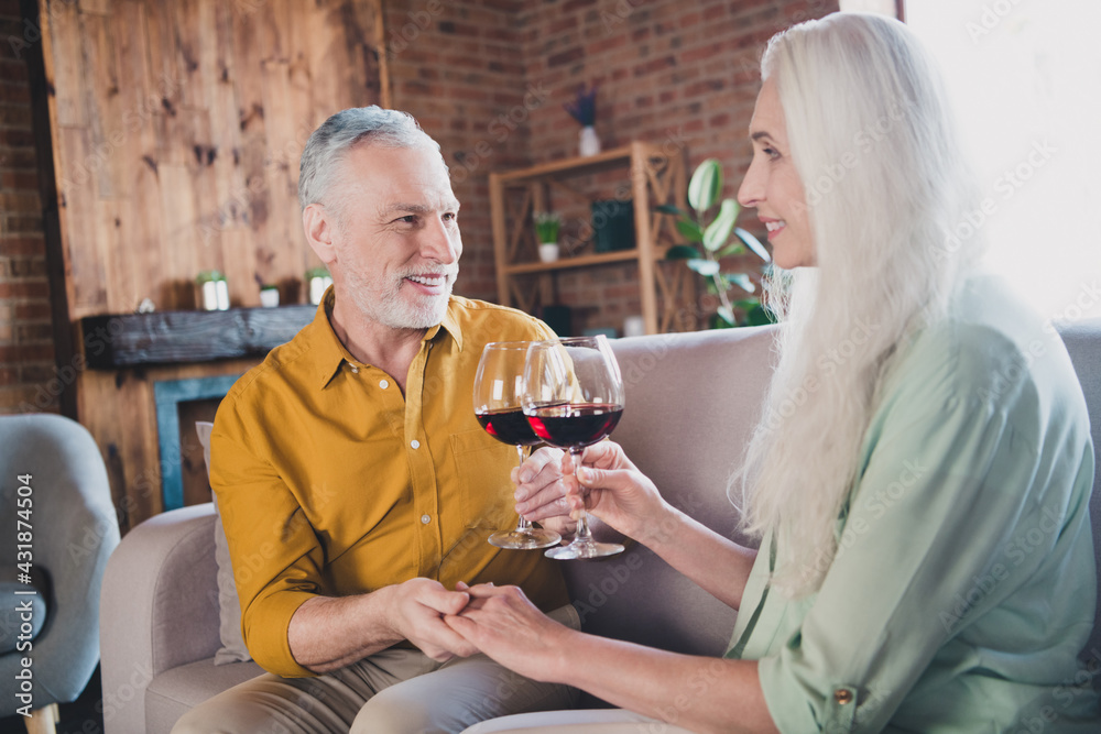 Portrait of attractive cheerful couple sitting on sofa drinking wine valentine day at loft industrial interior home indoor - obrazy, fototapety, plakaty 