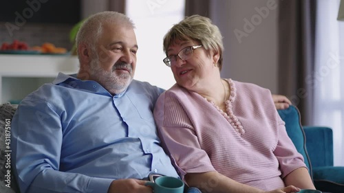 Wallpaper Mural cheerful mature man and woman are sitting on couch in apartment and communicating cheerfully, drinking tea and remembering Torontodigital.ca