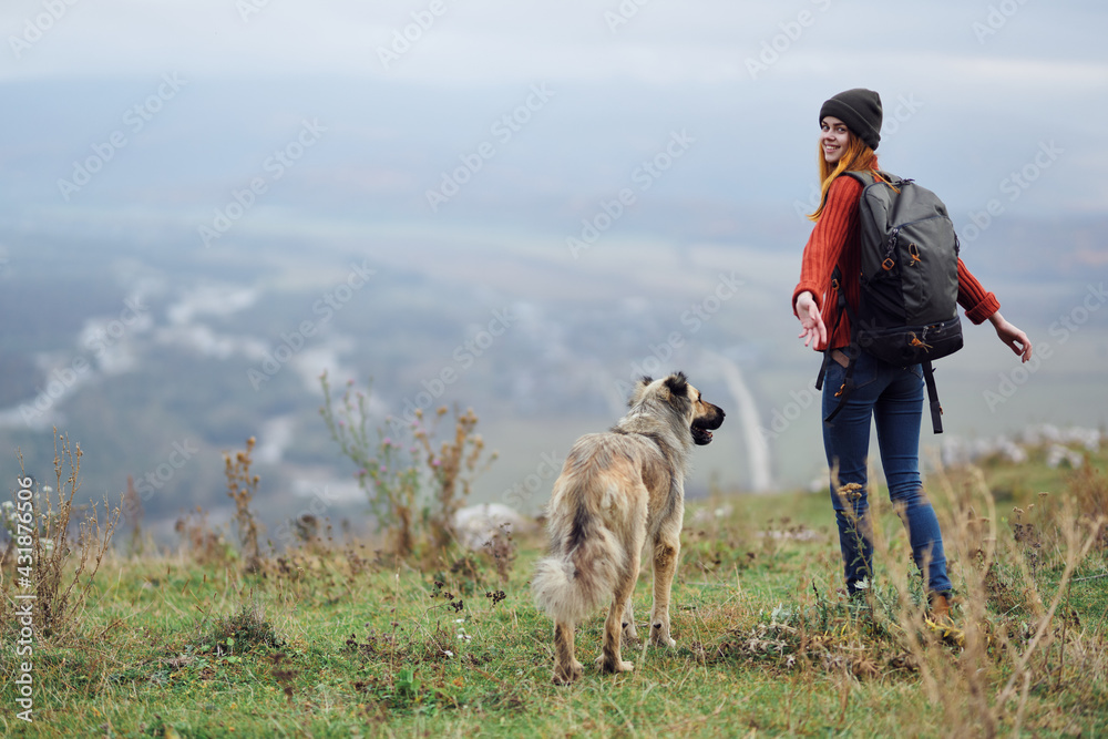 Fototapeta premium woman hiker with backpack with dog in the mountains travel friendship
