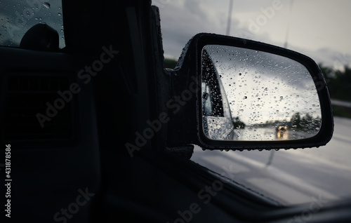 Selective focus of raindrops and reflection in side rear view mirror during hard rain fall.Rainy season and travel concept background. © chokchaipoo