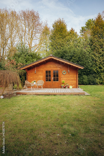Small wooden hut in the garden. Garden shed with a chair in front of the door. Nice wooden hut in the countryside in a small forest 