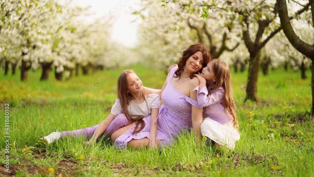 A family in a blossoming spring garden. mom and two daughters. slow motion. A family in a blossoming spring garden. mom and two daughters. slow motion.