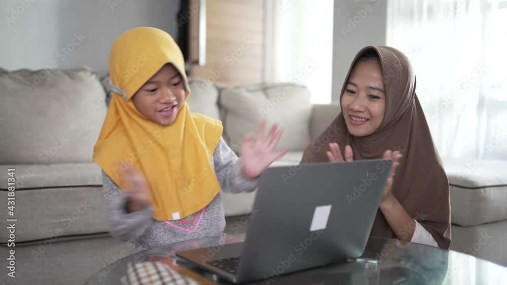 happy muslim mother and child singing and clapping together while using laptop together happy muslim mother and child singing and clapping together while using laptop together