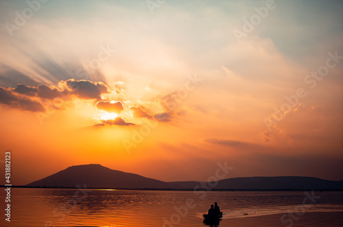 A beautiful golden sunset on the lake. Locals ride in a boat on a lake during a beautiful sunset. Sunset or sunrise landscape  panorama of beautiful nature.