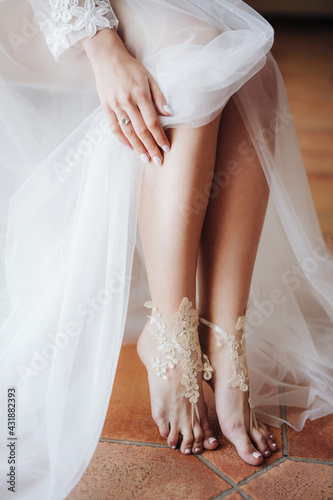Bride in white wedding dress opened bare feet. Close up © Nadtochiy