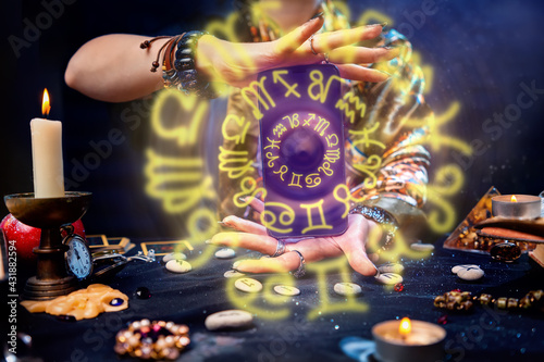 A fortune teller holds a smartphone in her hands, from which luminous zodiac circles fly out. Close-up. The concept of astrology, magic and esotericism