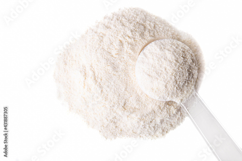 Heap of white protein powder with measuring spoon photo