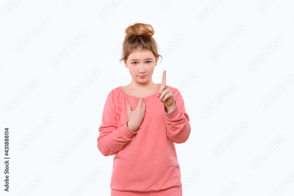Cute young girl in pink casual sweatshirt points at herself with hand in surprise. White background Cute young girl in pink casual sweatshirt points at herself with hand in surprise. White background
