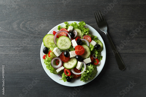 Plate of greek salad and fork on dark wooden background