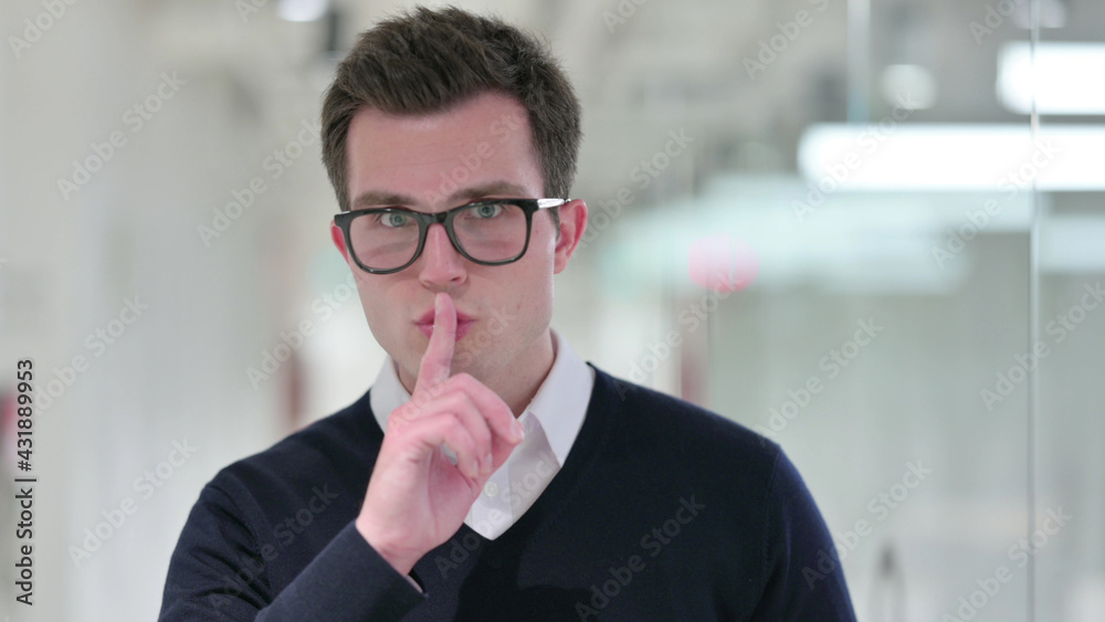 Serious Young Businessman Putting Finger on Lips Serious Young Businessman Putting Finger on Lips
