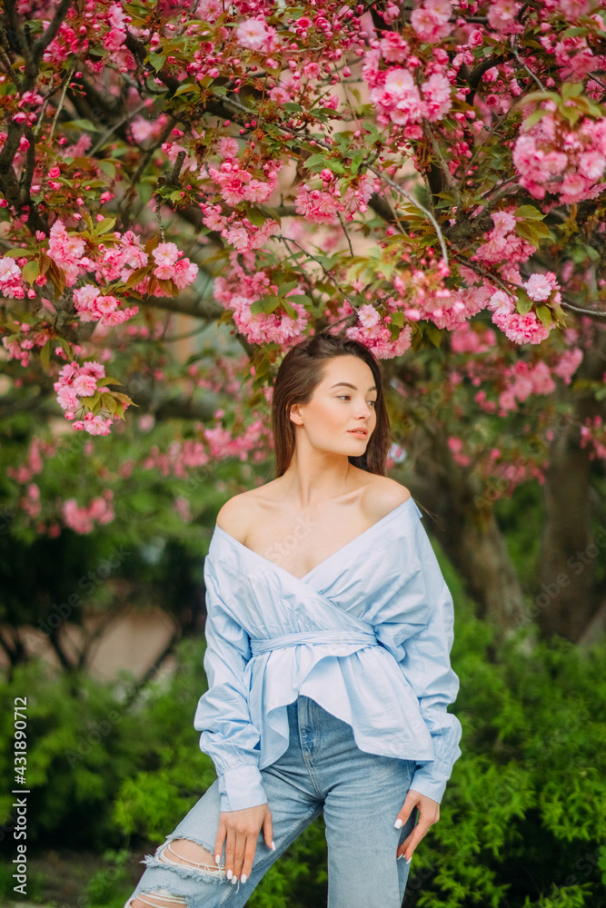 Woman walks in park with blooming sakura trees Woman walks in park with blooming sakura trees