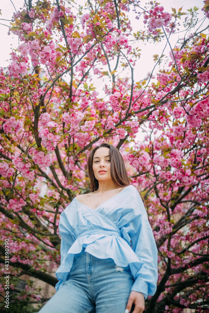 Woman walks in park with blooming sakura trees Woman walks in park with blooming sakura trees