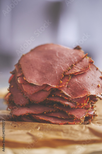 Fresh and delicious stack of sliced pastrami meat placed on wooden cutting board