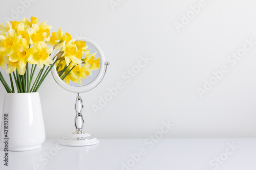 Fototapeta Naklejka Na Ścianę i Meble -  Daffodils in vase and reflection of yellow flowers in  mirror on white background