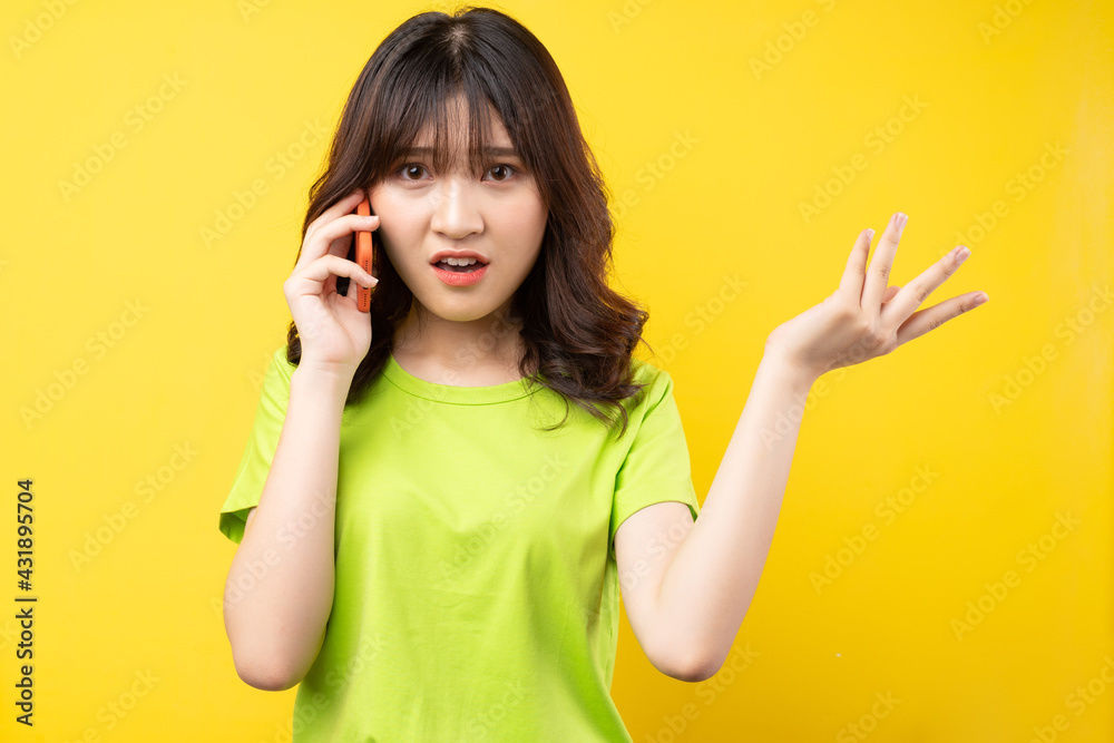 The young Asian girl was on the phone with an annoyed expression The young Asian girl was on the phone with an annoyed expression