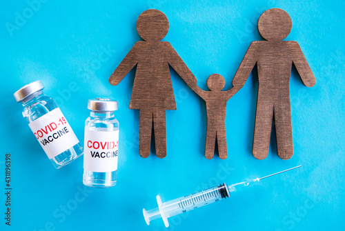 Family cut out and covid 19 vaccines lay on the table. Concept of family immunization. Coronavirus vaccine for children and parents