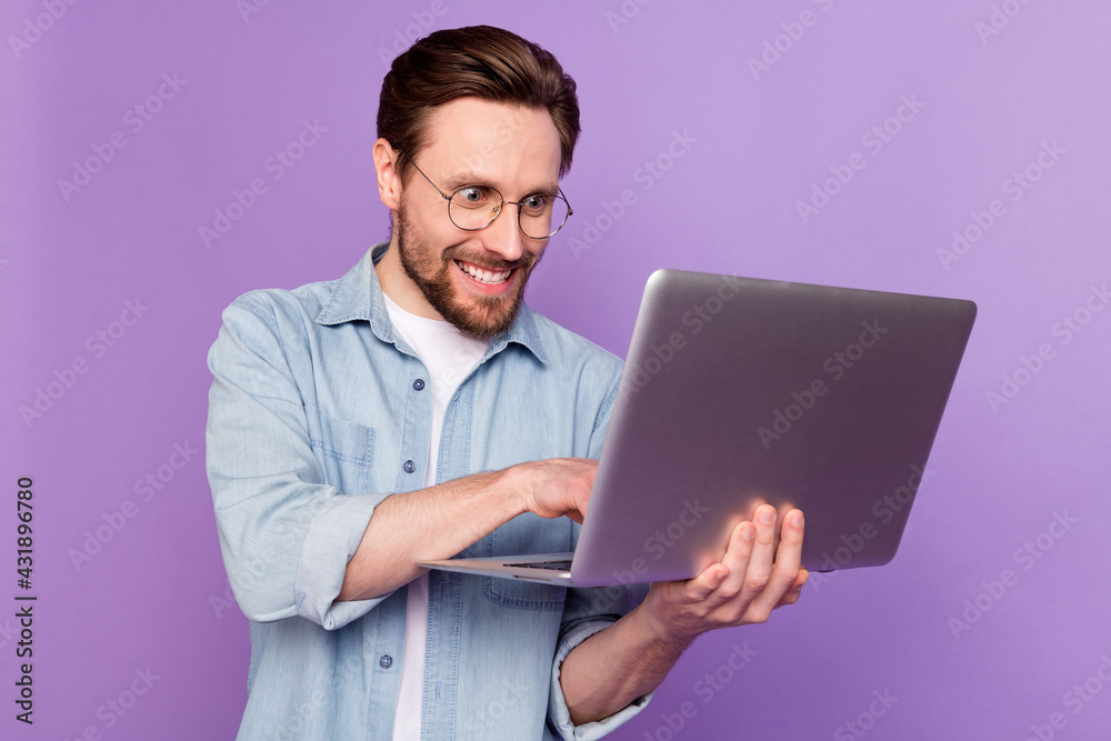 Photo of crazy young happy programmer man look hold laptop work plan isolated on purple color background Photo of crazy young happy programmer man look hold laptop work plan isolated on purple color background